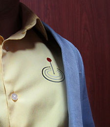 A close-up of the Formation Finder icon stitched onto a yellow shirt